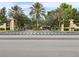 Elegant gated community entrance with palm trees, manicured landscaping, and decorative stone pillars at 6936 Hochad Dr, Orlando, FL 32819