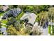 Aerial view of a green home with a screened-in pool, driveway, and lush green landscaping at 701 Palenci Ct, Winter Springs, FL 32708