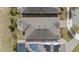 Aerial view of a home featuring solar panels, a pool, a patio with a fire pit, and a well-manicured yard at 7977 Hanson Bay Pl, Kissimmee, FL 34747