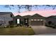 Dusk exterior of a well-maintained home with a paver driveway and manicured lawn at 7977 Hanson Bay Pl, Kissimmee, FL 34747