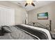 Cozy bedroom showcasing an iron bed frame, ceiling fan, closet, and wall mounted television at 9122 Stromboli Ct, Kissimmee, FL 34747