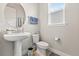 Charming powder room with pedestal sink, stylish mirror, and natural light from the window at 9947 Summerlake Groves St, Winter Garden, FL 34787