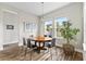 Bright dining room featuring a round wood table, stylish chandelier, and natural light from large windows at 9947 Summerlake Groves St, Winter Garden, FL 34787