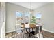 Bright dining room featuring a round wood table, stylish chandelier, and natural light from large windows at 9947 Summerlake Groves St, Winter Garden, FL 34787