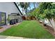 This backyard features a lush green lawn, an outdoor kitchen with a grill, and mature trees at 1296 Bridlebrook Dr, Casselberry, FL 32707