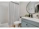 Bathroom featuring shower and tub with modern vanity, round mirror, and stylish black and white striped shower curtain at 1296 Bridlebrook Dr, Casselberry, FL 32707