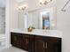 Elegant bathroom with a dual sink vanity featuring dark wood cabinets, white countertops, and stylish lighting fixtures at 15469 Shorebird Ln, Winter Garden, FL 34787