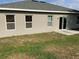 Exterior view of the backyard with a patio, sliding glass doors, and green lawn at 1958 Sawfish Dr, Kissimmee, FL 34759