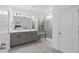 Modern bathroom with double sinks, a large mirror, gray cabinets, and a walk-in shower with glass doors at 2091 Brillante Dr, St Cloud, FL 34771