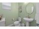 Charming half bath featuring a pedestal sink, toilet, and light green walls, complemented by a white blind at 2091 Brillante Dr, St Cloud, FL 34771