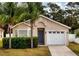 Charming home featuring a one-car garage and blue front door, complemented by lush landscaping at 2209 Hannah Ln, Orlando, FL 32826