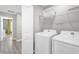 Bright laundry room with white washer, dryer, and storage shelving at 4431 Le Reve Ct, Kissimmee, FL 34746