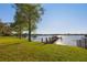 Landscaped backyard features lush lawn, mature trees, and a private dock with a boat lift on the lake at 535 Spring Club Dr, Altamonte Springs, FL 32714