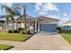 Attractive single-story home featuring lush green grass, palm trees, covered entryway and a neutral gray garage at 5571 Sycamore Canyon Dr, Kissimmee, FL 34758