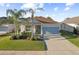 Welcoming single-story home with a well-maintained lawn, palm trees, covered entrance, and a two-car garage at 5571 Sycamore Canyon Dr, Kissimmee, FL 34758