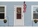 Close up on the front door with welcome sign, American flag, and floral arrangements at 655 W Date St, Lake Wales, FL 33859