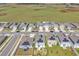 An aerial view of neighborhood homes featuring solar panels, green lawns, and a big field in the background at 659 Daring Dr, Davenport, FL 33837