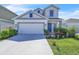 Charming two-story home with a well-manicured lawn, two-car garage, and eye-catching blue door at 659 Daring Dr, Davenport, FL 33837