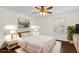 Cozy staged bedroom featuring dark hardwood flooring, a ceiling fan, and a window with white shutters at 729 Strihal Loop, Oakland, FL 34787