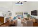 Staged living room showcases hardwood floors, vaulted ceiling, and a serene view of the outdoor landscape at 729 Strihal Loop, Oakland, FL 34787