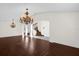 Bright living room featuring dark wood floors, two chandeliers, and staircase with open entryway at 729 Strihal Loop, Oakland, FL 34787