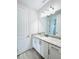 Bathroom featuring granite countertop, white cabinets, a framed mirror, and wood-look tile flooring at 7717 Graben St, Kissimmee, FL 34747