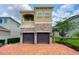 Charming two-story home featuring a stone facade, balcony, and a two-car garage with brick paver driveway at 7717 Graben St, Kissimmee, FL 34747