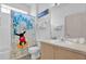 Playful bathroom featuring a tub with a Mickey Mouse shower curtain and a vanity with ample counter space at 8136 Fan Palm Way, Kissimmee, FL 34747