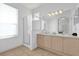 Well-lit bathroom featuring a double sink vanity, a glass-enclosed shower, and neutral tile flooring at 8136 Fan Palm Way, Kissimmee, FL 34747