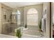 Beautiful bathroom features a glass enclosed shower, soaking tub, and a bright arched window at 8534 Black Mesa Dr, Orlando, FL 32829