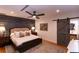 Comfortable bedroom with rustic accent wall, ceiling fan, wood floors, and a sliding barn door to bathroom at 8929 Charleston Park # 12, Orlando, FL 32819