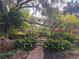 Lush, vibrant garden with colorful flowers, mature trees, and a charming walkway at 116 Crown Oaks Way # 116, Longwood, FL 32779