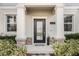 Inviting front porch with decorative columns, manicured landscaping, and a stylish glass paneled front door at 12024 Sonnet Ave, Orlando, FL 32832