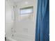 All-white bathroom with tub/shower combination, window, and blue curtain at 12820 Butler Bay Ct, Windermere, FL 34786