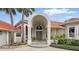 Front entrance with an arched portico, gray door, manicured landscaping, and a red tile roof at 12820 Butler Bay Ct, Windermere, FL 34786