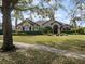 A warm-toned home with a tile roof, lush landscaping, and a spacious front yard viewed from the sidewalk at 12860 Jacob Grace Ct, Windermere, FL 34786