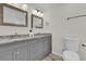 Bathroom featuring double vanity sinks with granite countertop and grey cabinetry at 13128 Devonshire Rd, Orlando, FL 32832