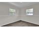 Bright bedroom featuring two windows, grey wood floors, and crisp white trim at 13128 Devonshire Rd, Orlando, FL 32832