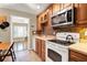 Kitchen with wooden cabinets, tiled backsplash, and white appliances, open to a sunny living room at 137 Spring Chase Cir, Altamonte Springs, FL 32714