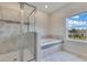 Bright bathroom features a walk-in shower, soaking tub, and tiled walls at 1722 Lake Sims Pkwy, Ocoee, FL 34761