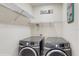 Laundry room with modern side-by-side washer and dryer and wire shelving at 1722 Lake Sims Pkwy, Ocoee, FL 34761