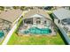 Aerial view of a screened in ground pool with chairs surrounded by green grass at 215 Elderberry Dr, Davenport, FL 33897