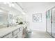 Bright bathroom featuring double sinks, decorative art, and a glass-enclosed shower with modern fixtures at 2305 Sirena Ln, Mount Dora, FL 32757