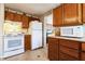 Functional kitchen featuring white appliances, wood cabinetry, and vinyl flooring at 24813 E Highway 316, Salt Springs, FL 32134