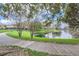 Scenic view of a community pond with walking path and surrounding trees at 2847 Metro Sevilla Dr # 103, Orlando, FL 32835