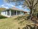 View of the home's backyard featuring a screened-in porch, lush lawn, and mature shade trees at 3726 Mount Hope Loop, Leesburg, FL 34748