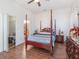 Bedroom with wood floors, canopy bed, bedside tables, and closet door leading to bath at 3726 Mount Hope Loop, Leesburg, FL 34748