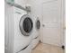 Bright laundry room showcasing a modern, side-by-side washer and dryer unit, next to a white door at 3726 Mount Hope Loop, Leesburg, FL 34748