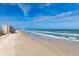 Wide shot of a sandy beach and coastline, with a building visible in the background at 4495 S Atlantic Ave # 5020, Ponce Inlet, FL 32127