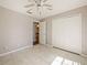 Bright bedroom featuring tile flooring, a ceiling fan, and double-door closet for ample storage at 527 Buckhaven Loop, Ocoee, FL 34761